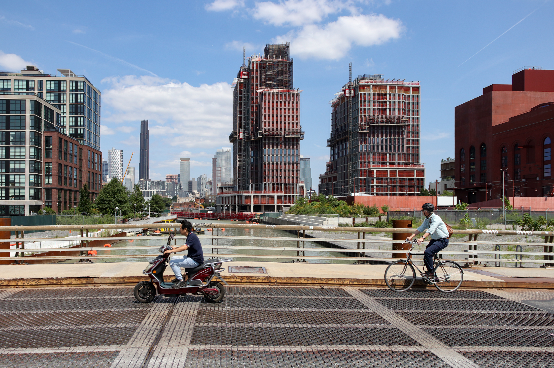 bike riders crossing the 3rd street bridge with towwers in the background