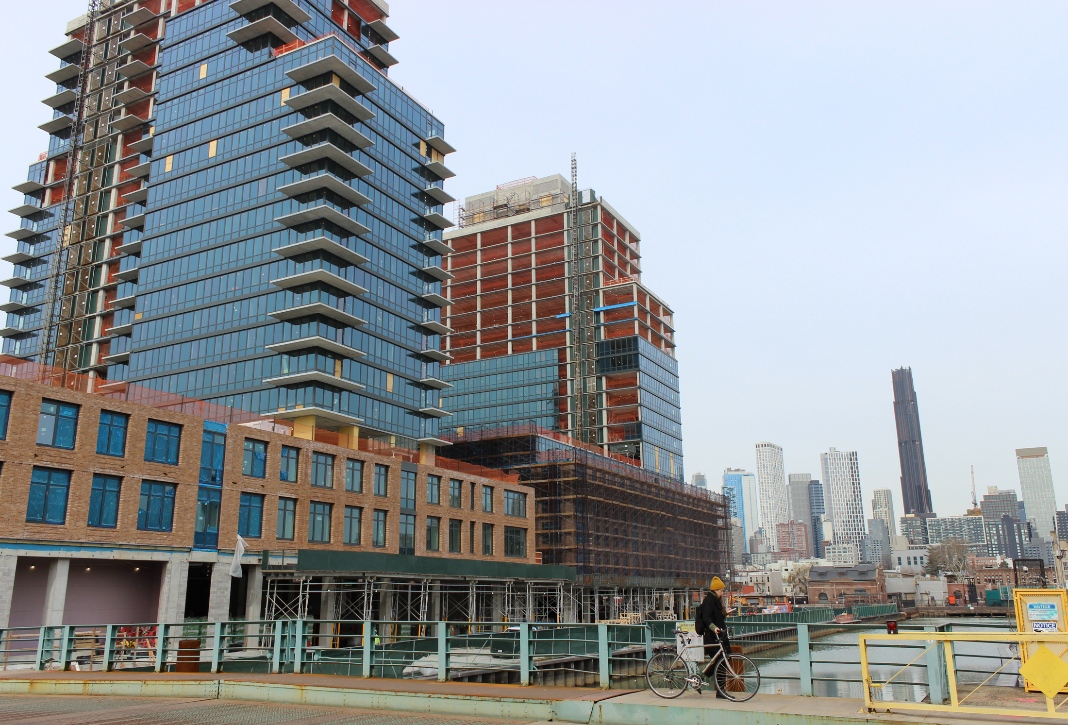 person with bike on the bridge with construction rising behind