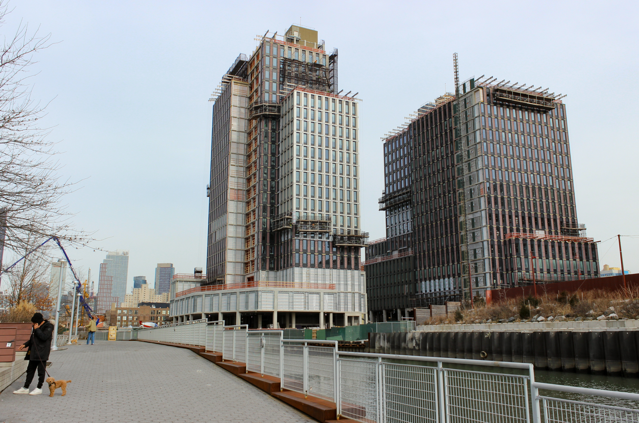 person walking a dog with towers and canal behind