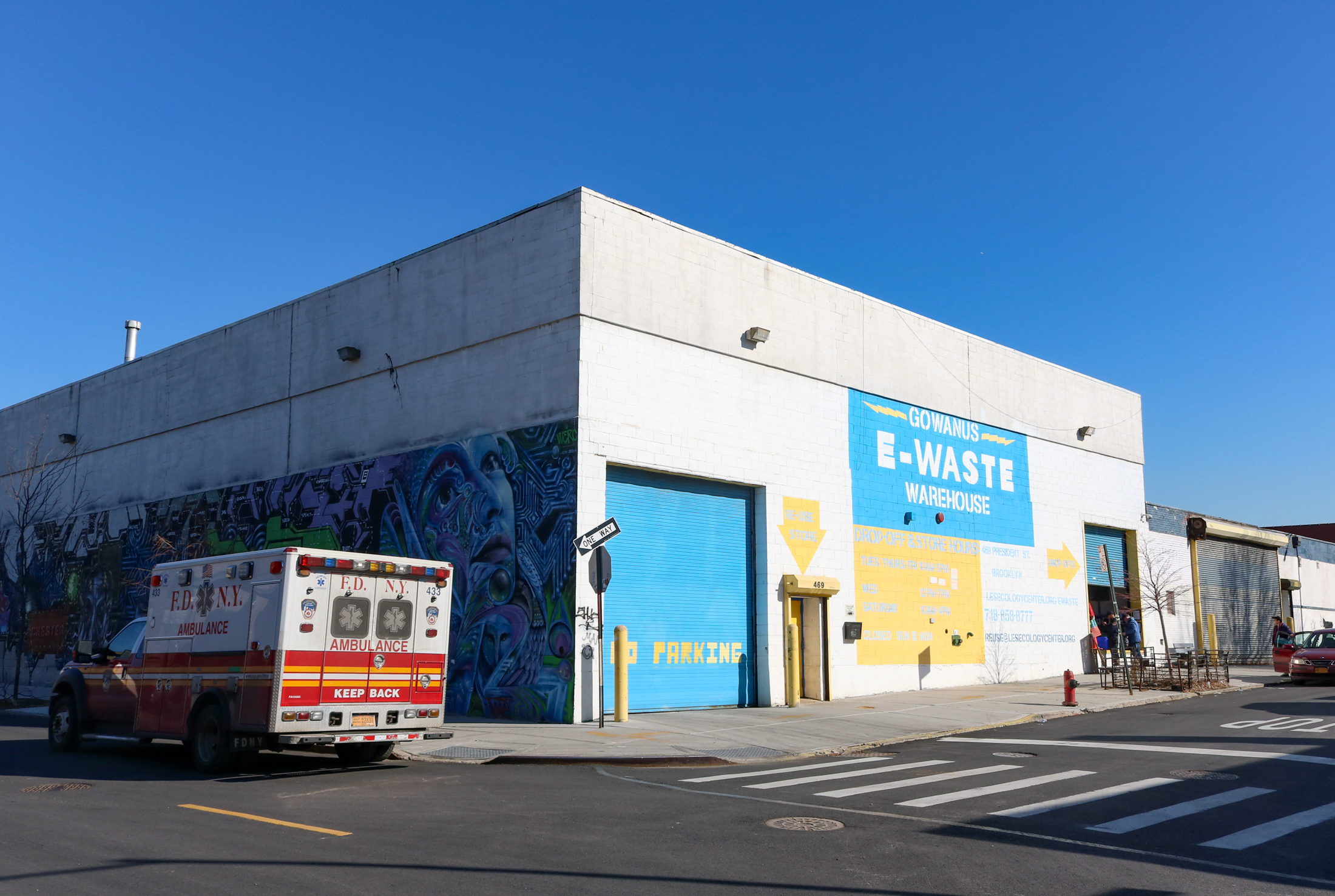 low scale building with mural on one side and painted sign for gowanus e-waste on the other