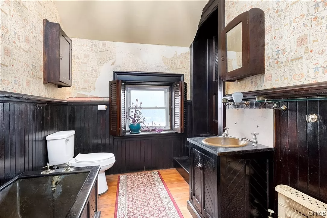 bathroom with wood vanity, marble sink, copper tub and wood floor
