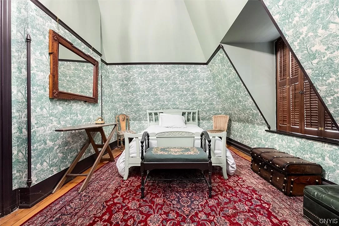 bedroom with angled walls and green tree wallpaper