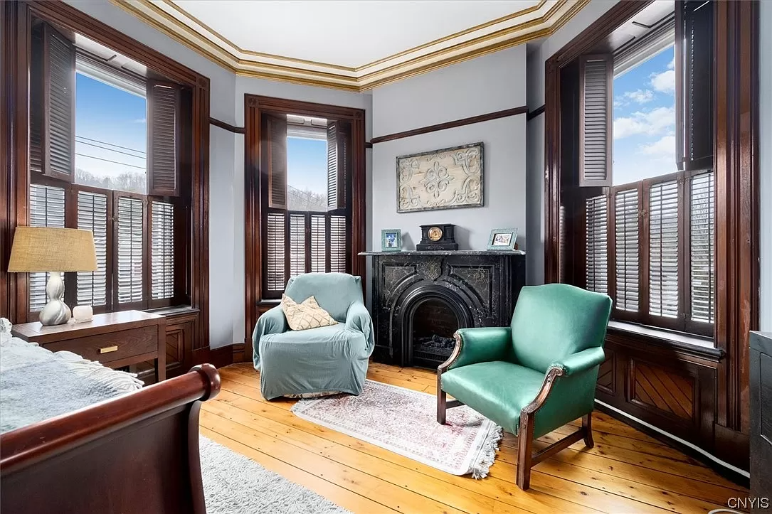 corner bedroom with black mantel and three windows