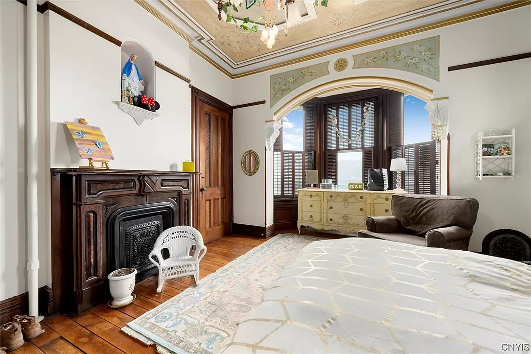 bedroom with bay window nook and a wood mantel