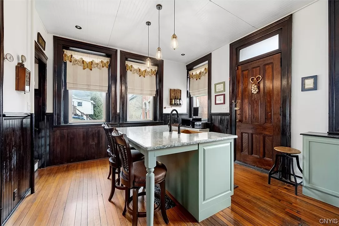 kitchen with wood floor, central island, wainscoting and door to exterior