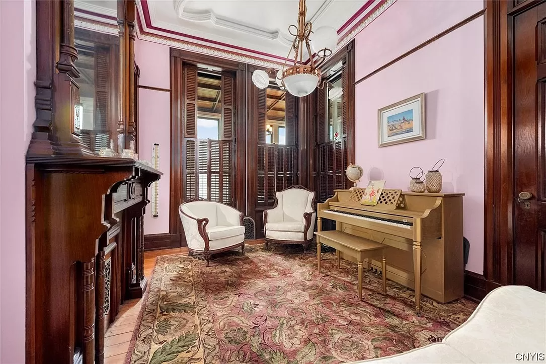 parlor with pink walls, a wood mantel and picture rails