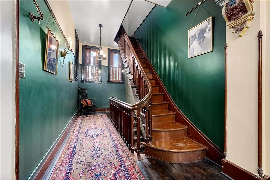 hall with curving staircase and dark green walls