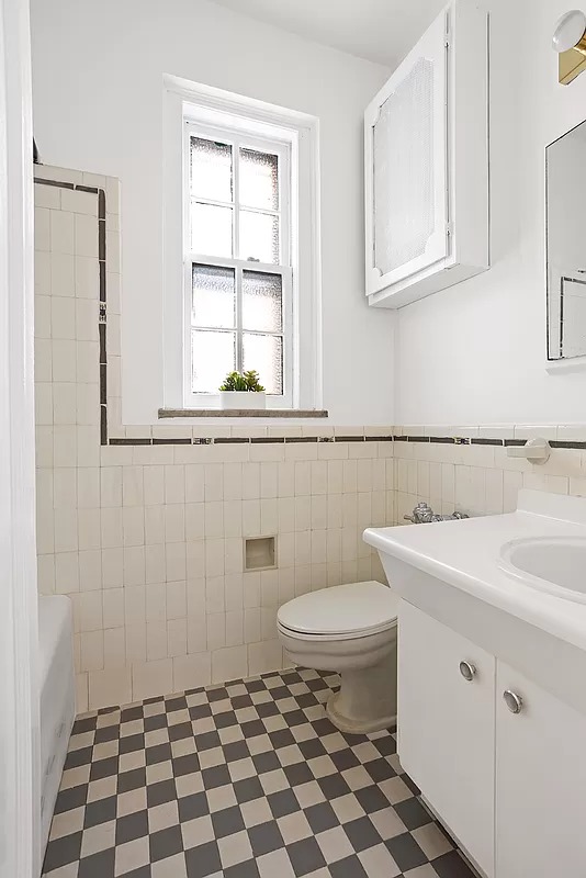 bathroom with checkerboard tile floor and white vertical subway tile