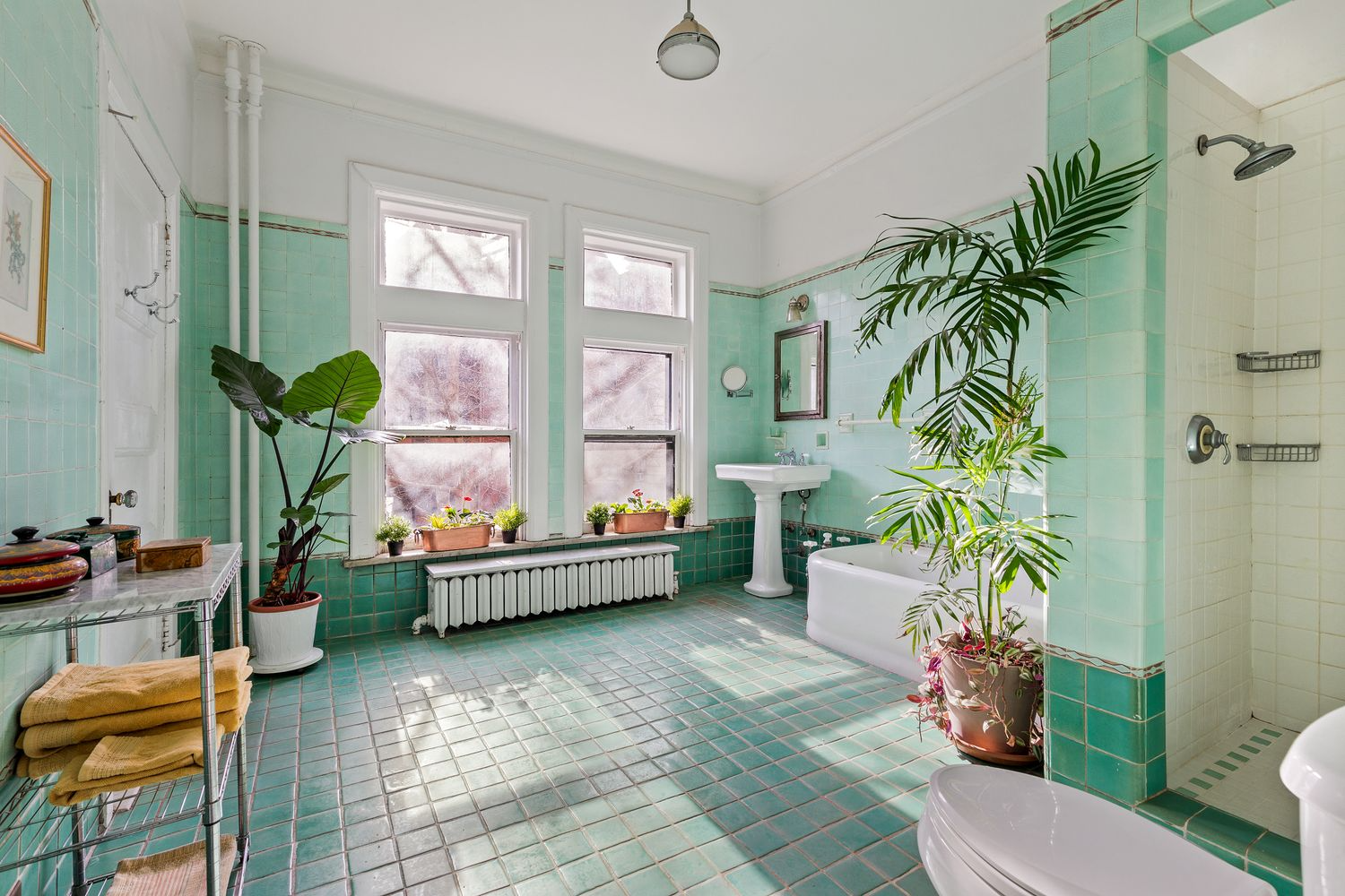 large bathroom with white fixtures and walls and floor of jade green tile