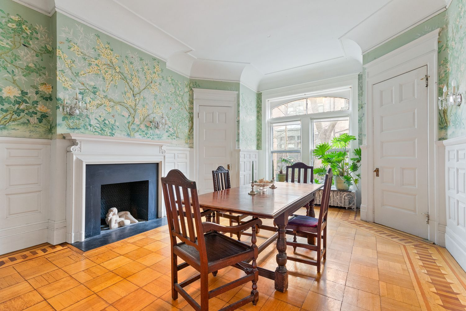dining room with wood floor, white wainscoting and pale green tree wallpaper