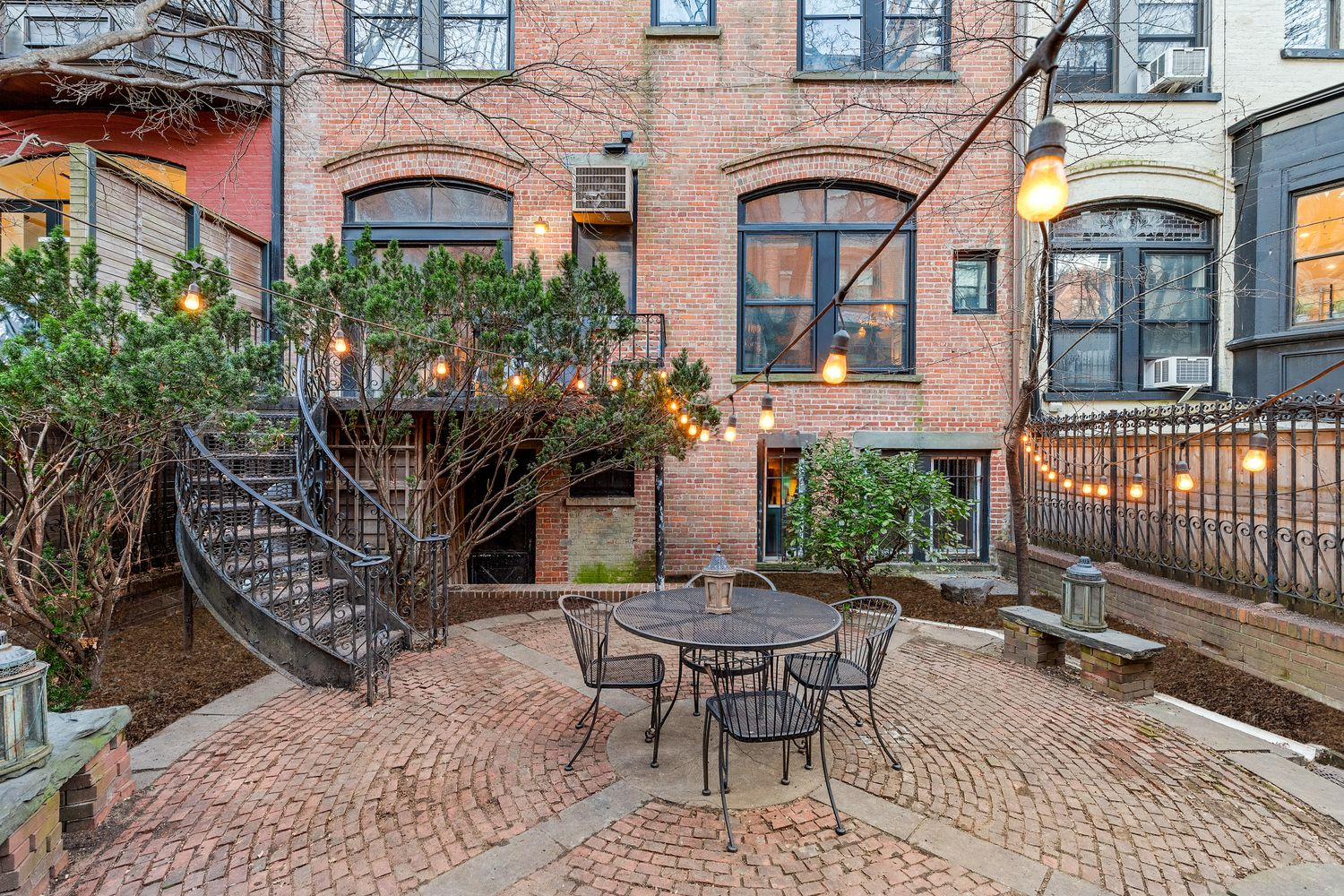 curved brick patio with planting beds on edges and stair down from deck