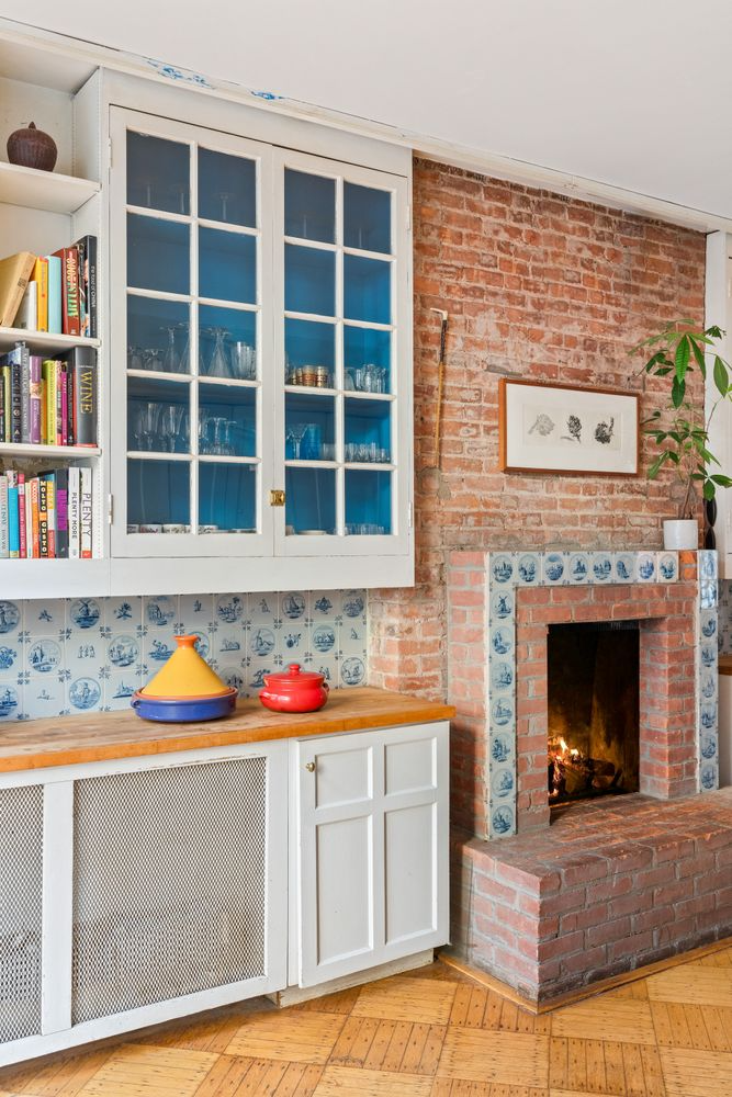 kitchen with brick fireplace, white cabinets and delft tile backsplash