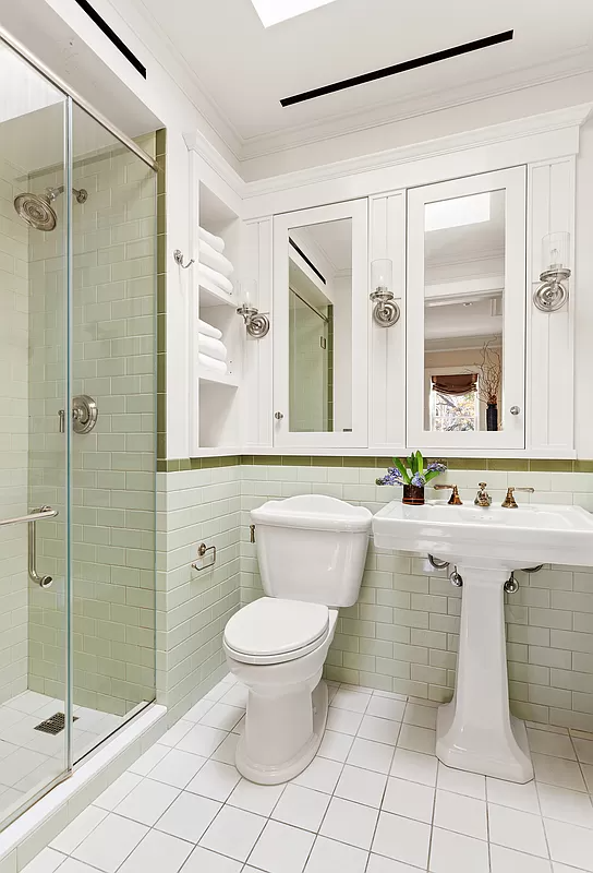 bathroom with pale green wall tiles and a shower with glass doors