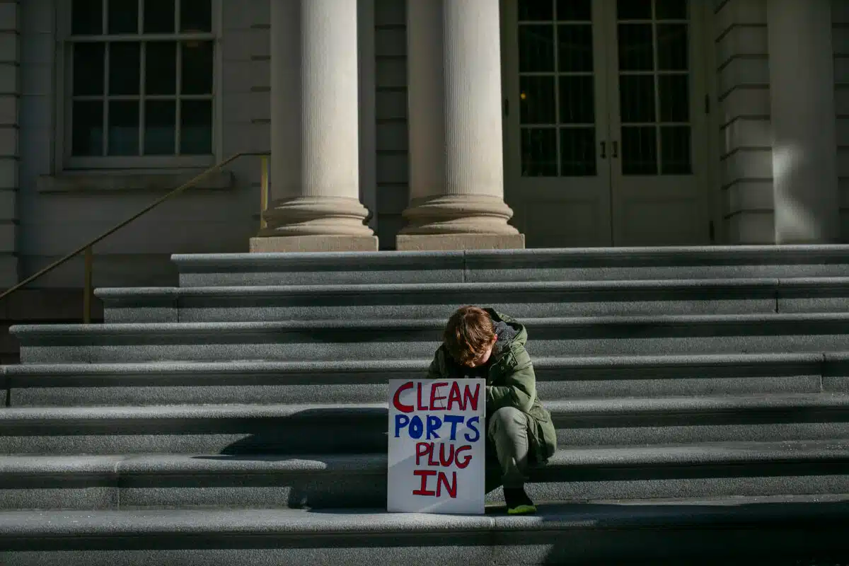 child on steps with a sign that says "clean ports plug in"