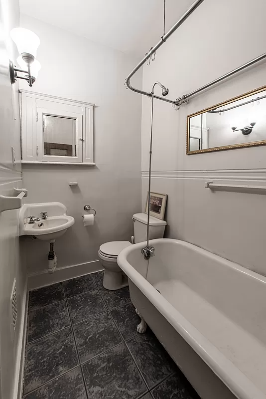 bathroom with small corner sink and a claw foot tub