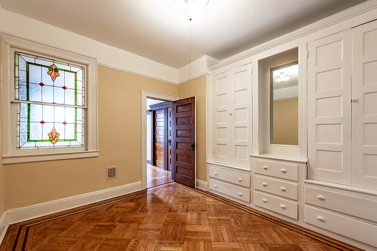 bedroom with stained glass window and wall of built-in storage