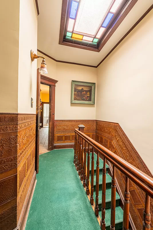 upstairs hallway with green carpet, skylight with stained glass