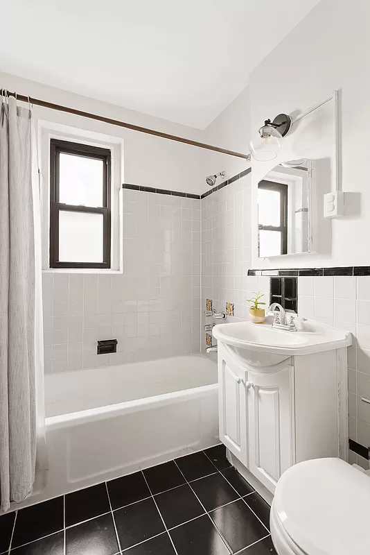 bathroom with white fixtures and black floor tile