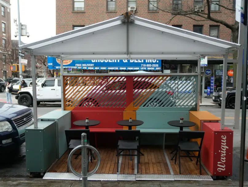 outdoor dining with wood slat floor and a colorful bench