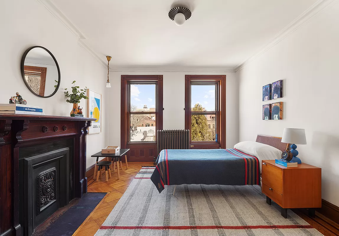 bedroom with wood floor and a mantel