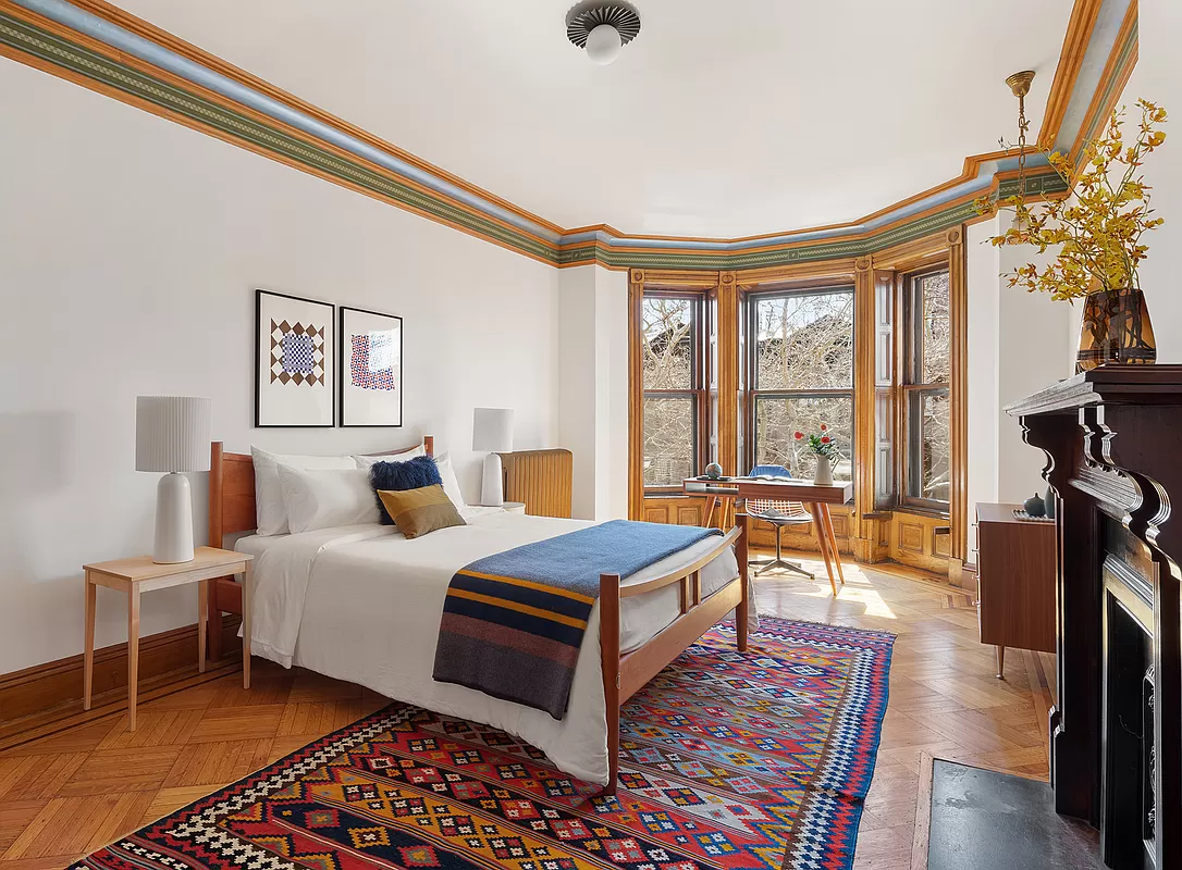 bedroom with wood floor, bay window and mantel