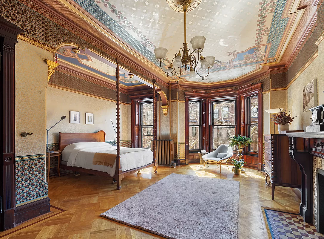 bedroom with bed niche, mantel and wallpaper on walls and ceiling