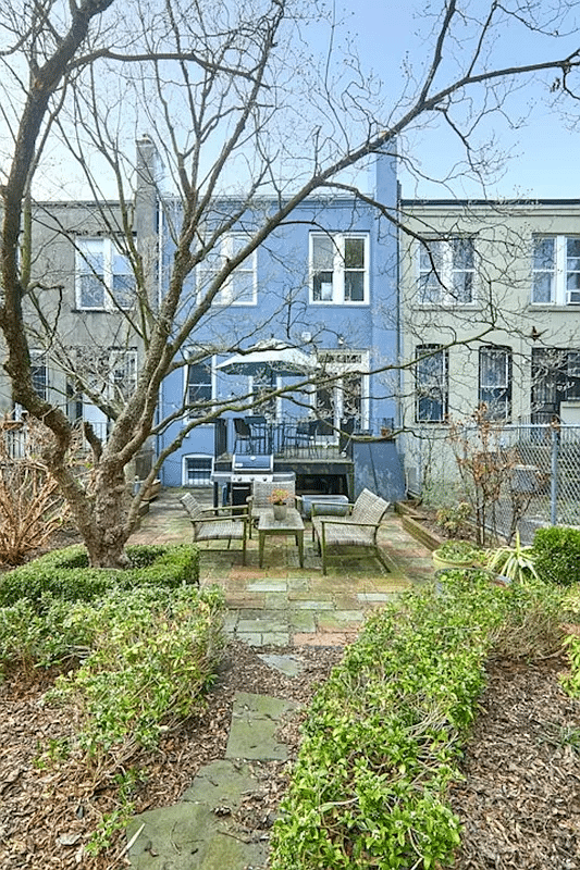 rear yard with a large tree, stone patio and some planting beds