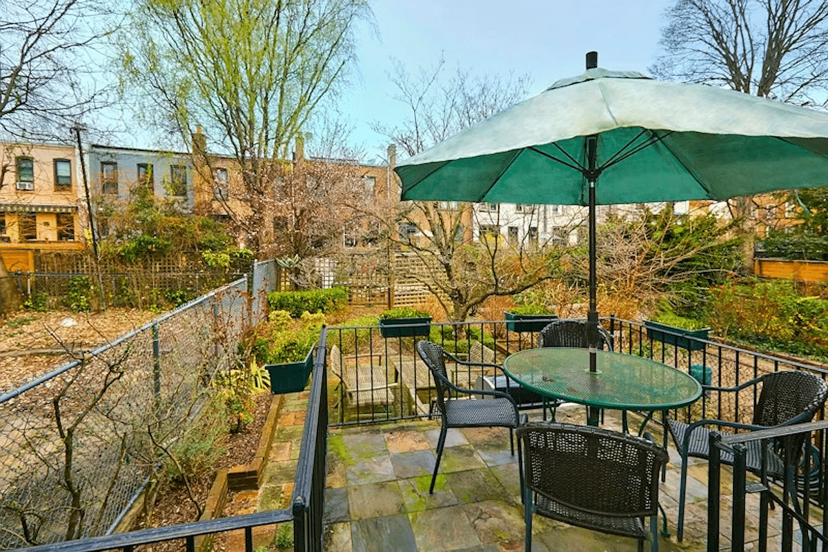 stone paved rear deck with iron rail and view to the rear garden
