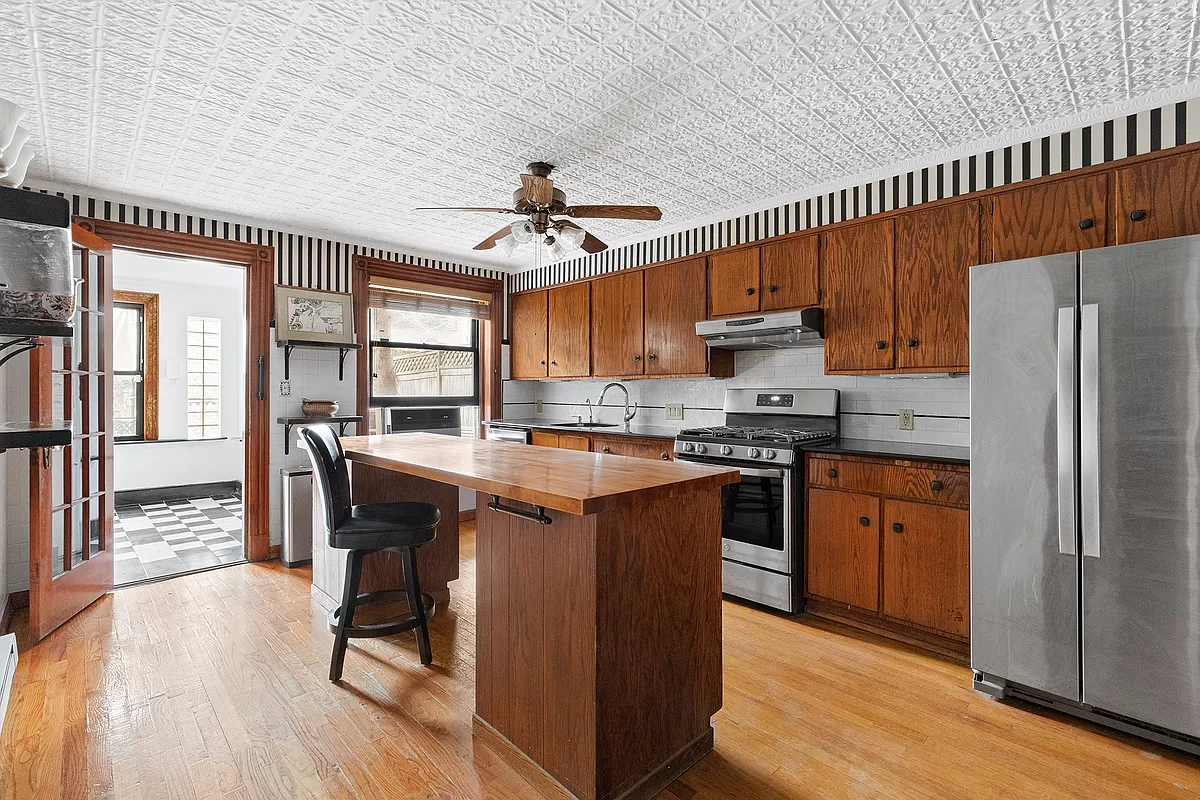 garden level kitchen with slab fronted wood cabinets, an island and a tin ceiling