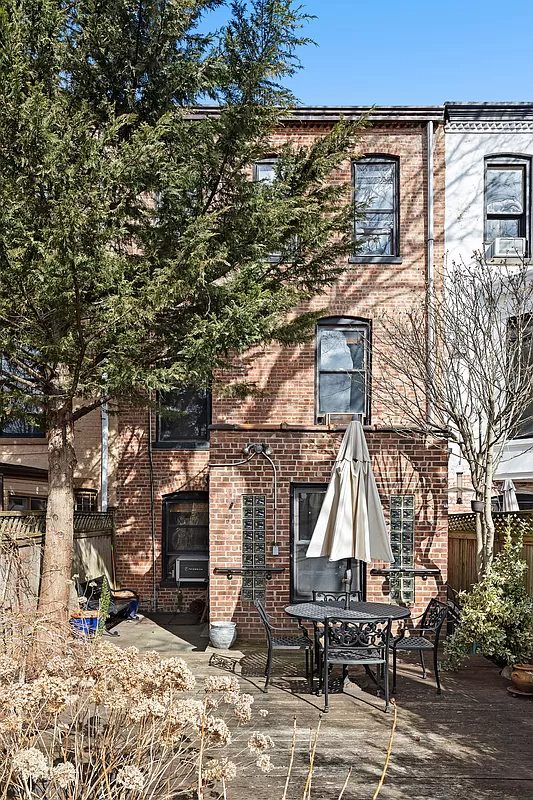 brick rear facade with view of wood deck