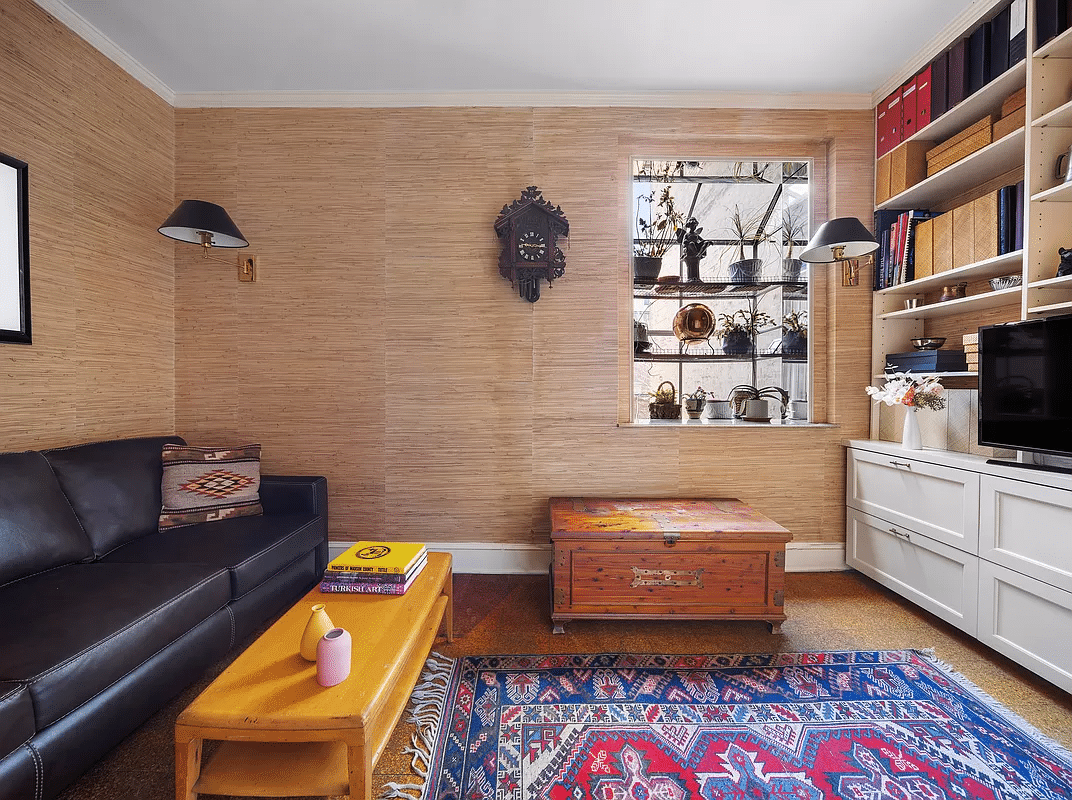 bedroom set up as a den with neutral wallpaper and built-in storage