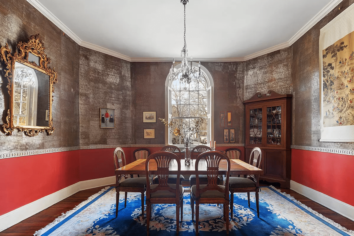 dining room with shimmering wallcovering above a chair rail and red paint below