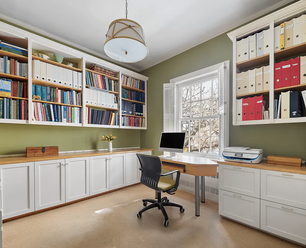 bedroom set up as an office with white cabinets and open shelves above