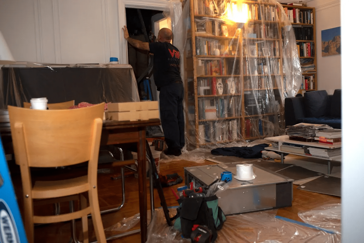 Workers install an electric heat pump inside an apartment at a pre-war Brooklyn Heights building