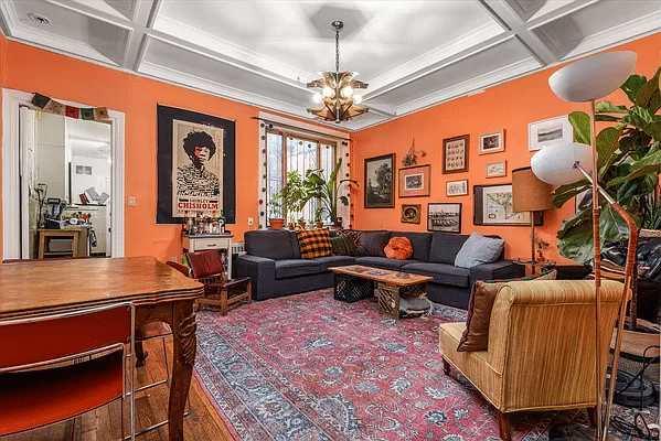 former dining room set up as a living room with beamed ceiling and orange walls