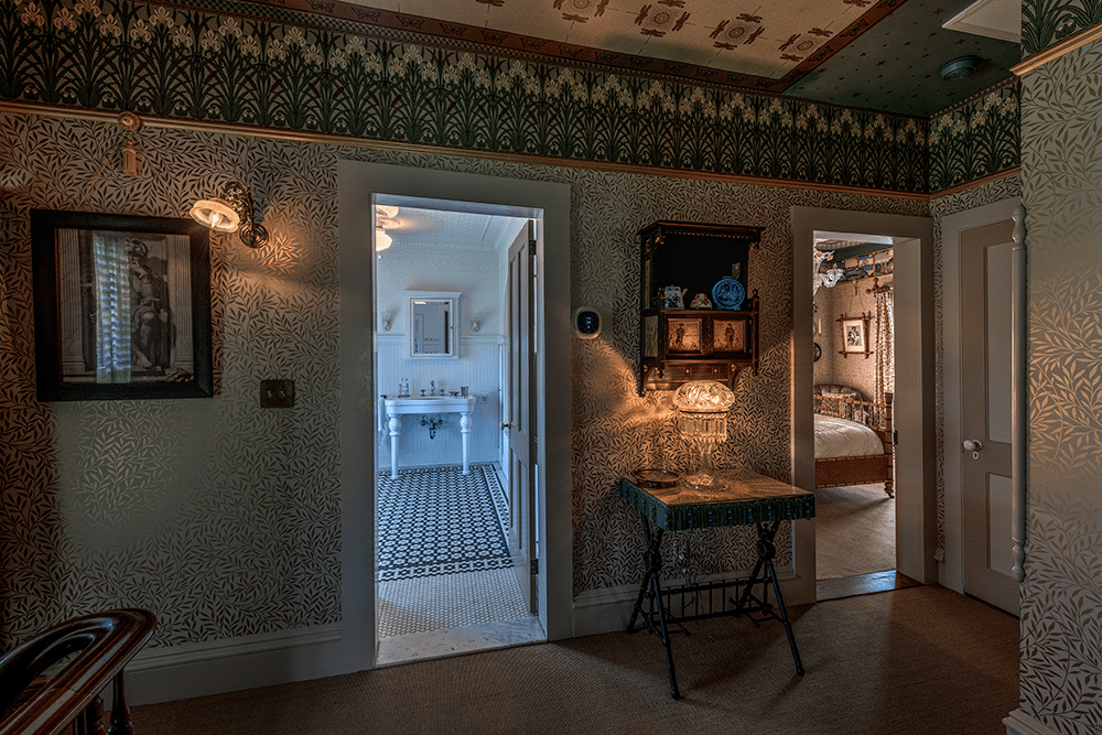 upstairs hall with wall and ceiling papers and view into bathroom