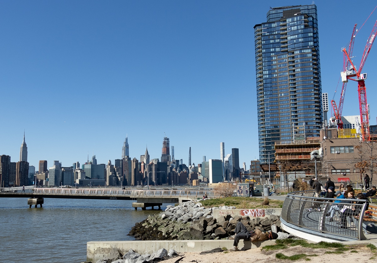 greenpoint - people sitting along the waterfront in Transmission park with Manhattan skyline in the distance