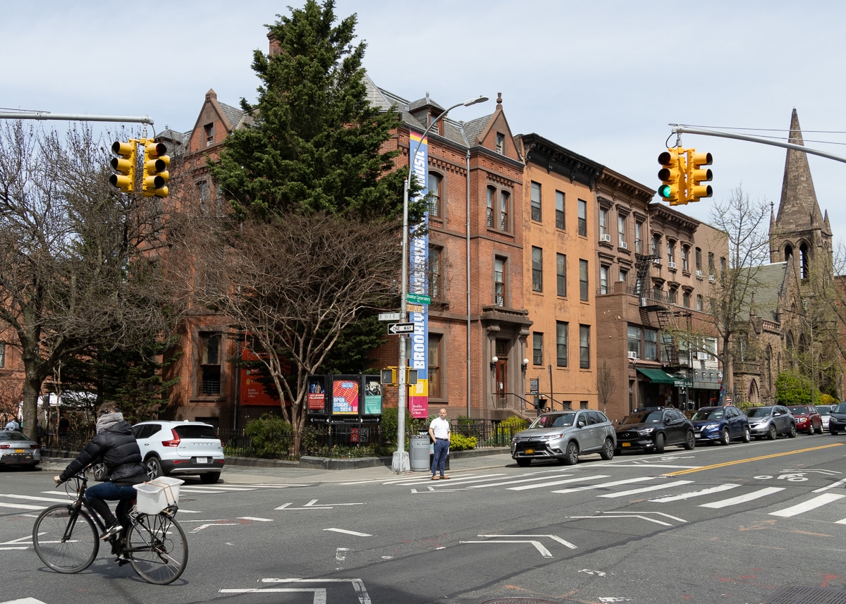 view on 7th avenue with person on a bike and brick and brownstone buildings
