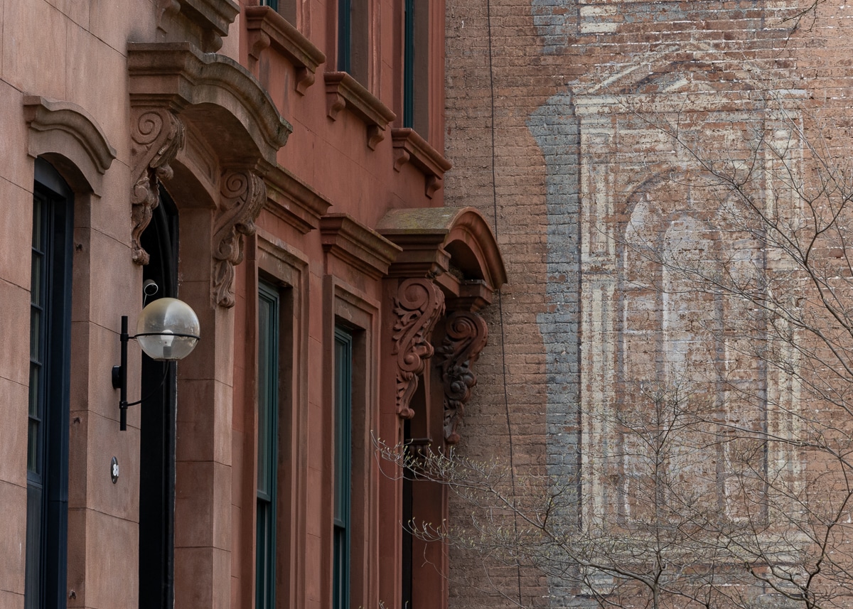 brooklyn - broownstone doorways with a faded mural on a brick wall