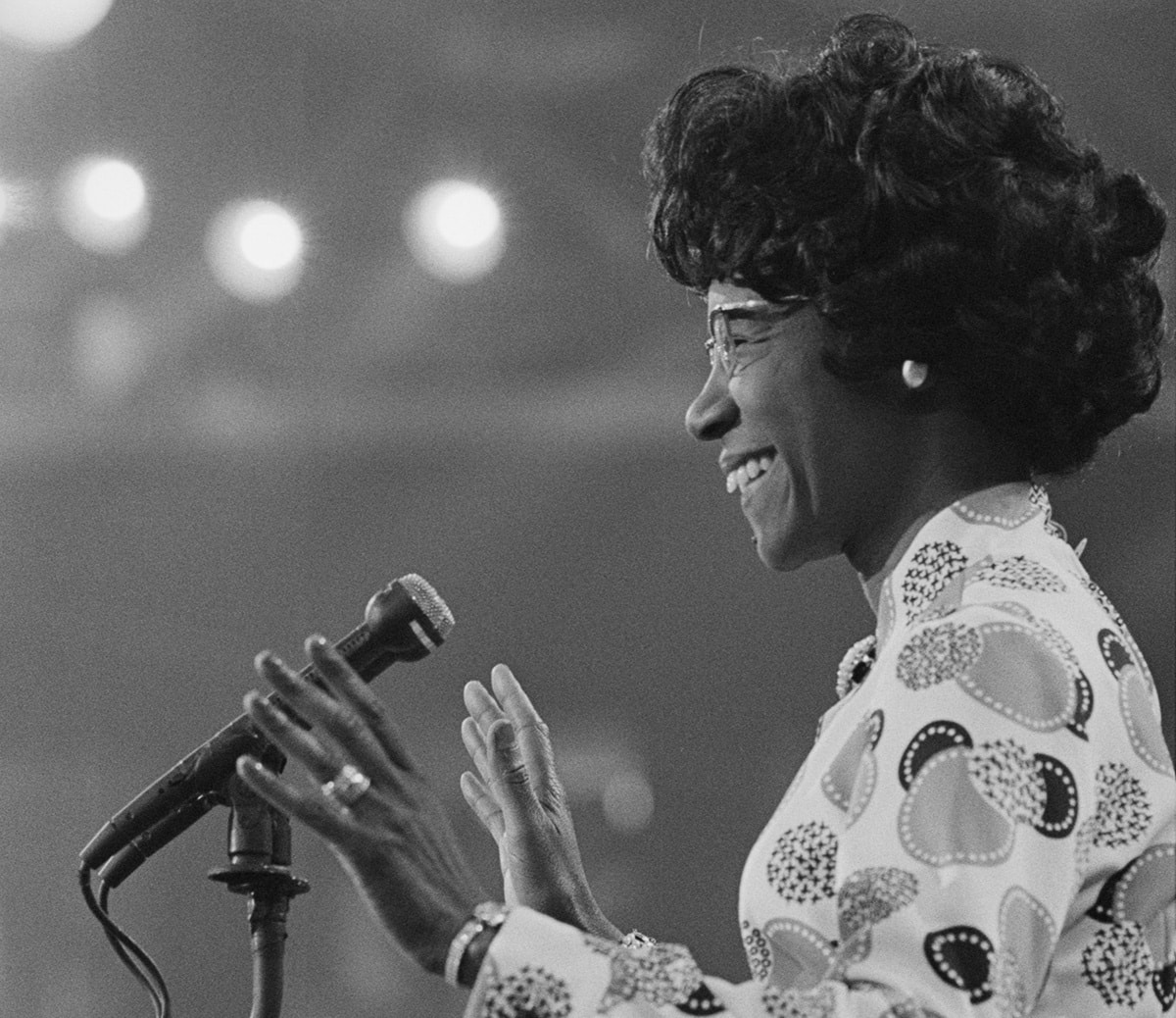 shirley chisholm - black and white photo of her at a podium with a microphone