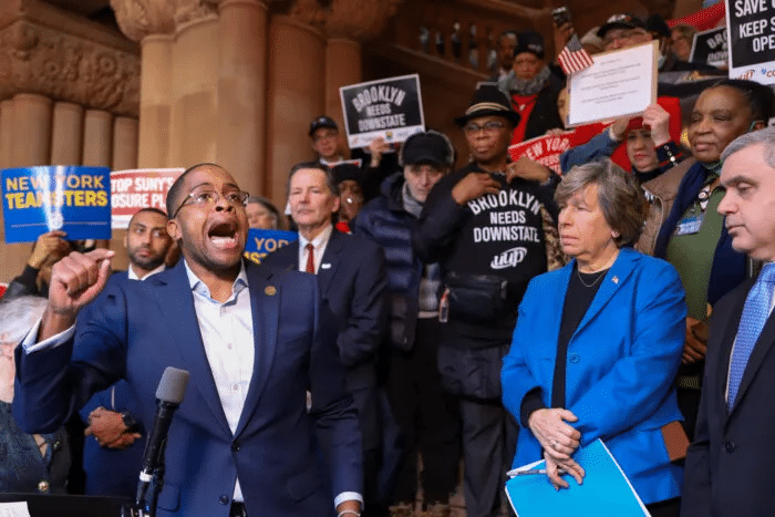 speaker at a microphone and others holding signs