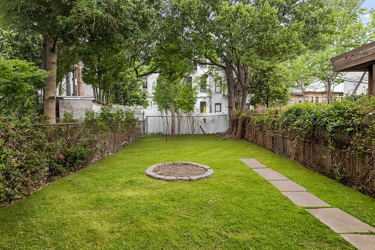 fenced in rear yard with grass and a large tree