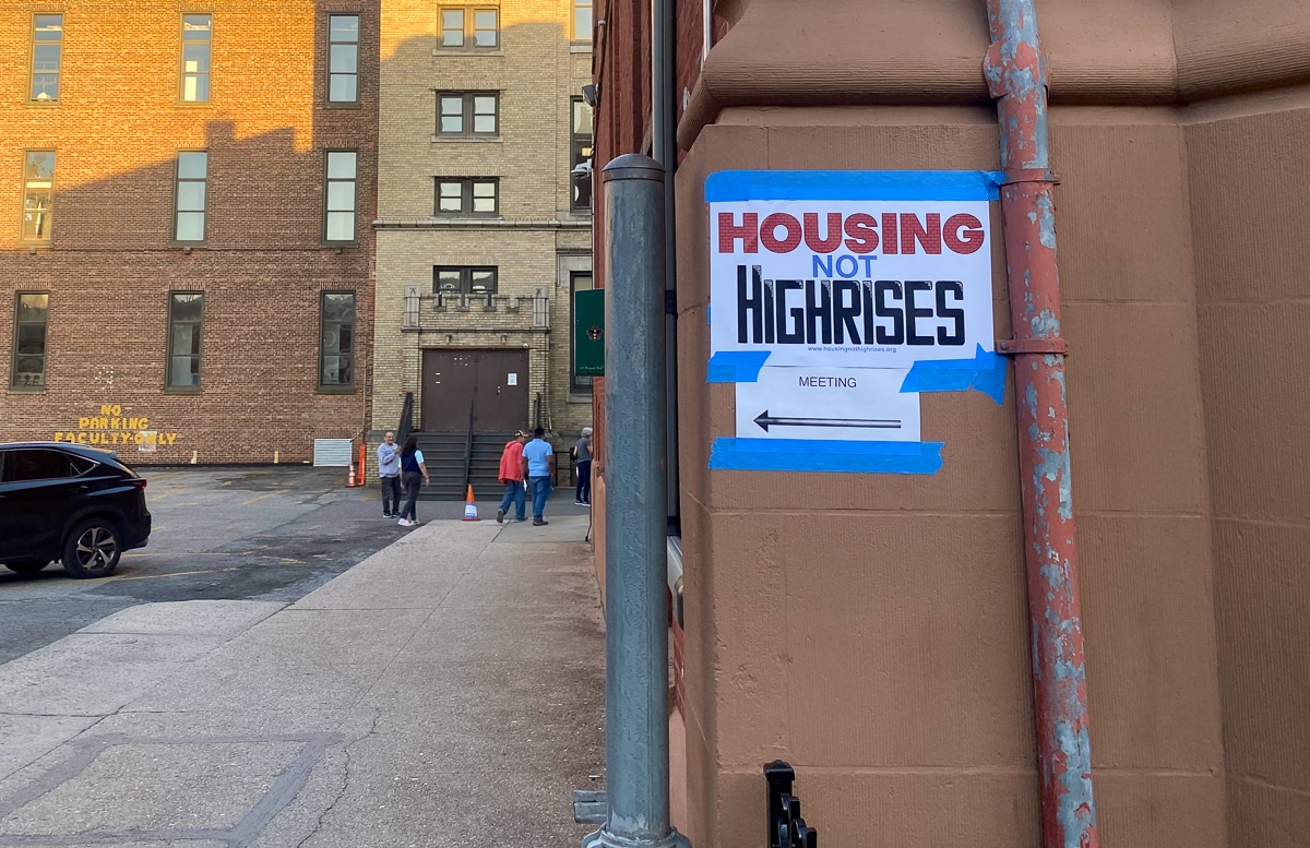 a "housing not highrises" sign outside the meeting location