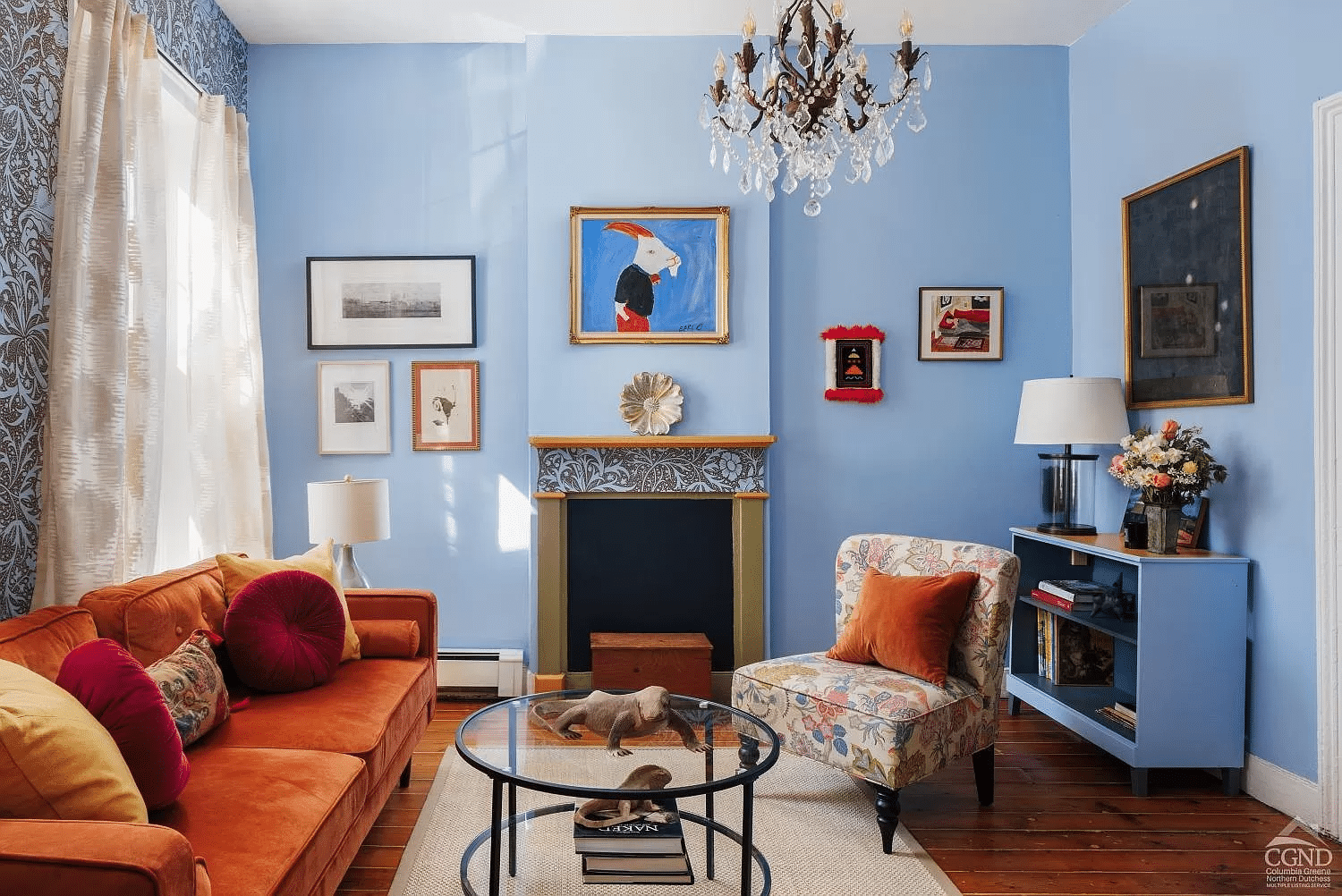 living room with blue walls and strip of blue floral wallpaper on the mantel