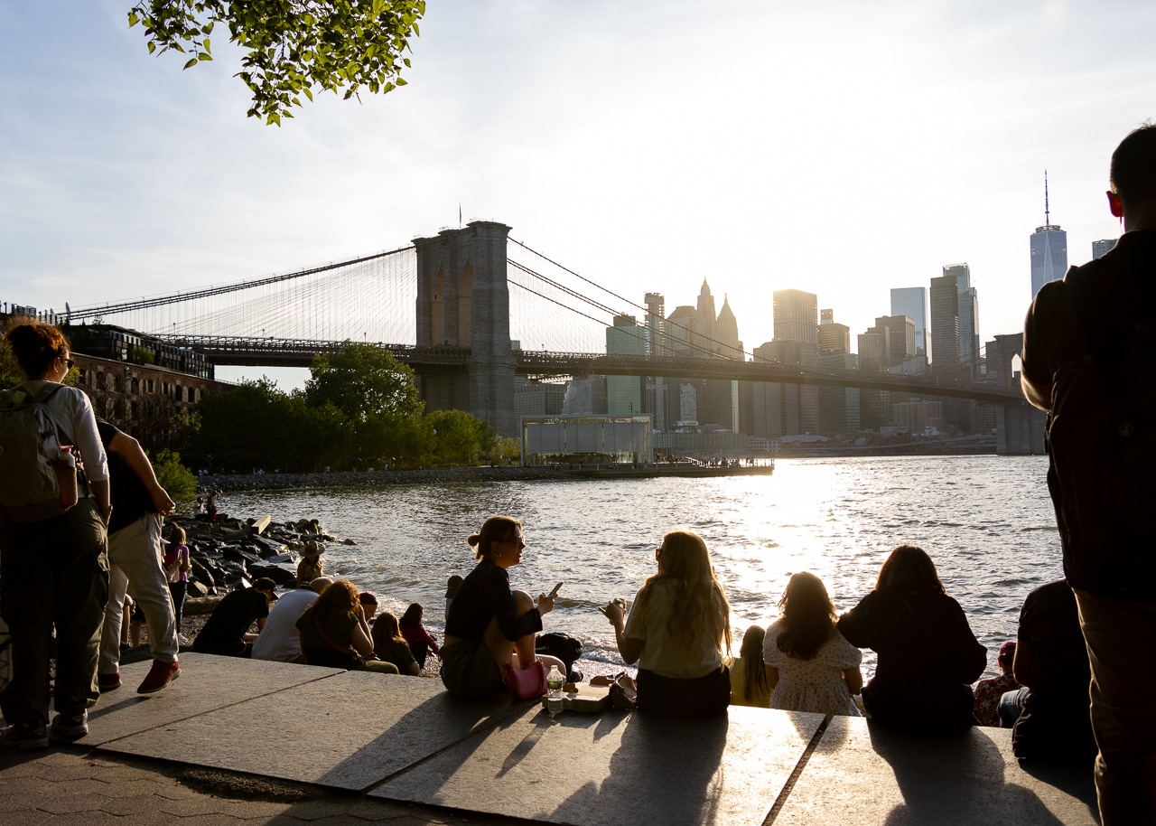 brooklyn - people sitting by the waterfront in brooklyn bridge park at sunset