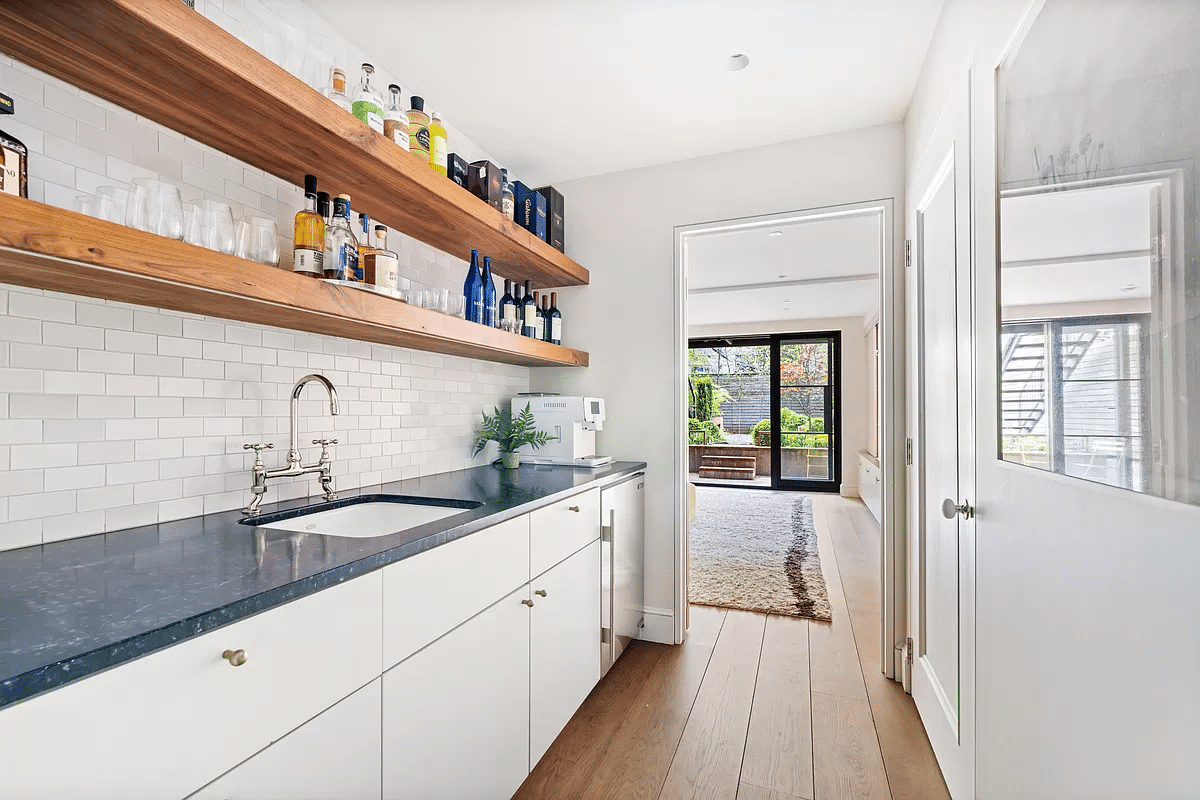 wet bar on the garden level with white cabinets, a sink, and small fridge
