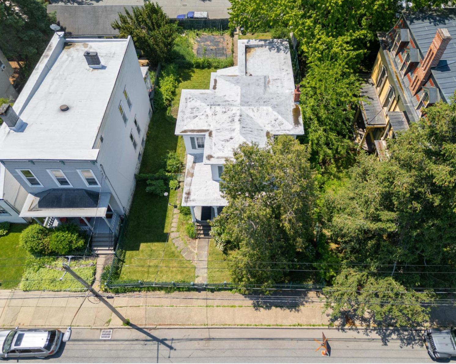 aerial view of the exterior of the white clapboard house with shutters and a picket fence