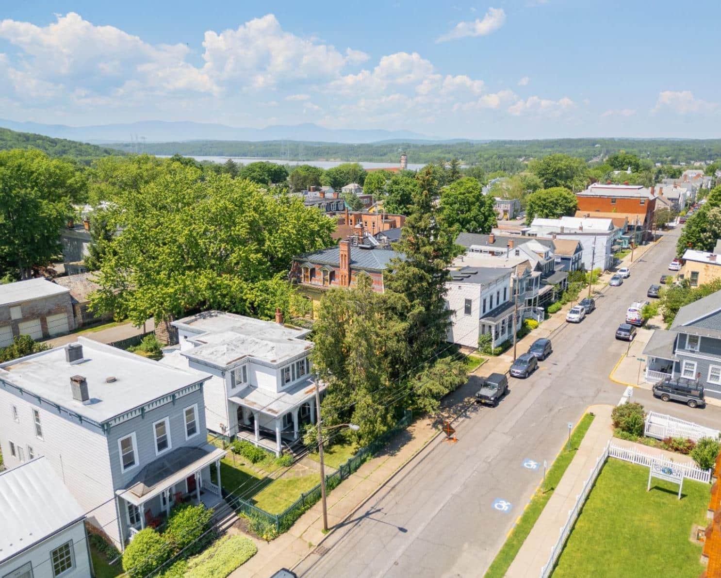 aerial view of the exterior of the white clapboard house with shutters and a picket fence