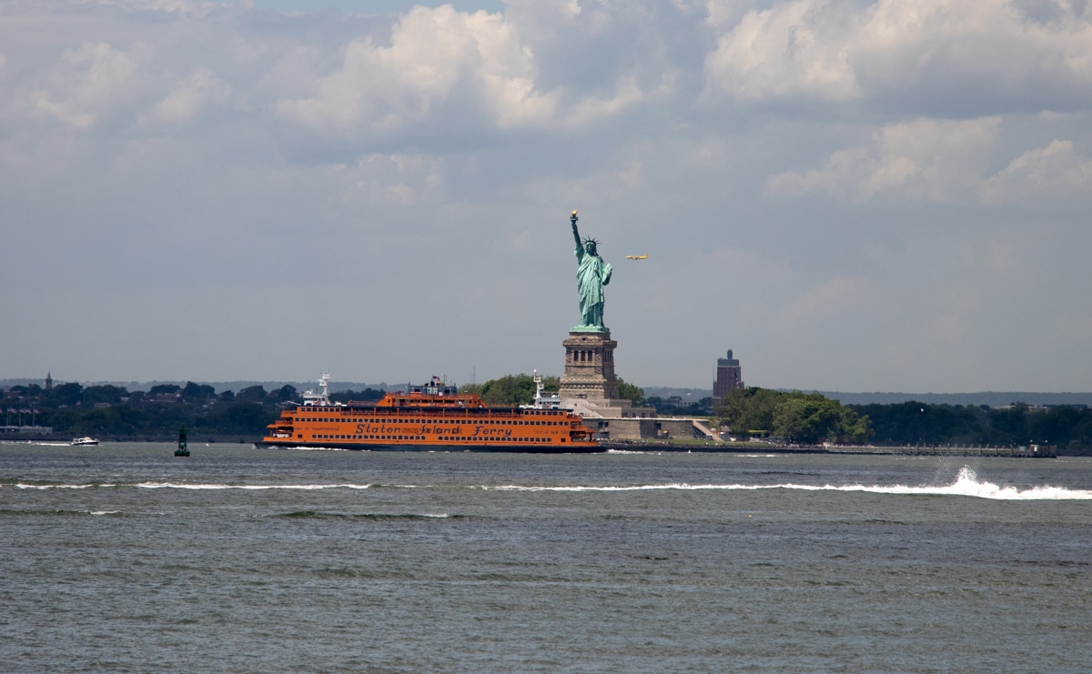 brooklyn - view from red hook with staten island ferry crossing in front of the statue of liberty