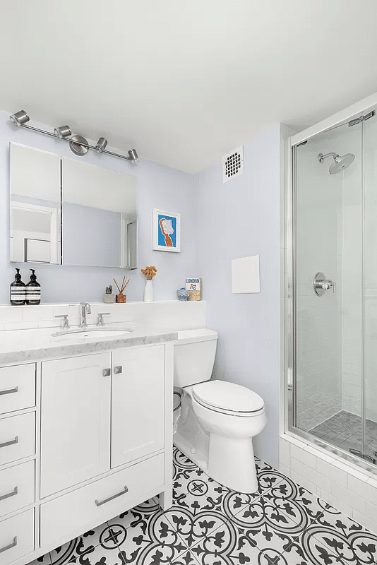 bathroom with black and white floor tile, white fixtures and a shower